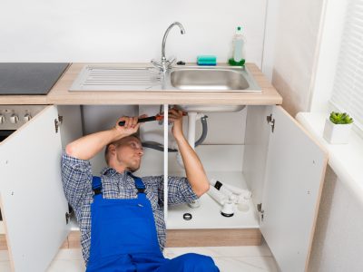 Plumber Repairing Sink In Kitchen