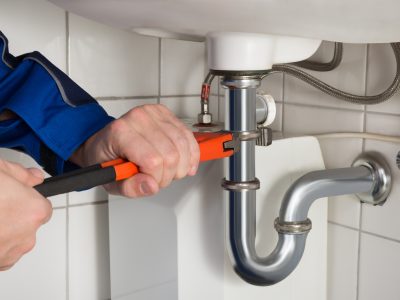 Male Plumber Repairing Sink In Bathroom